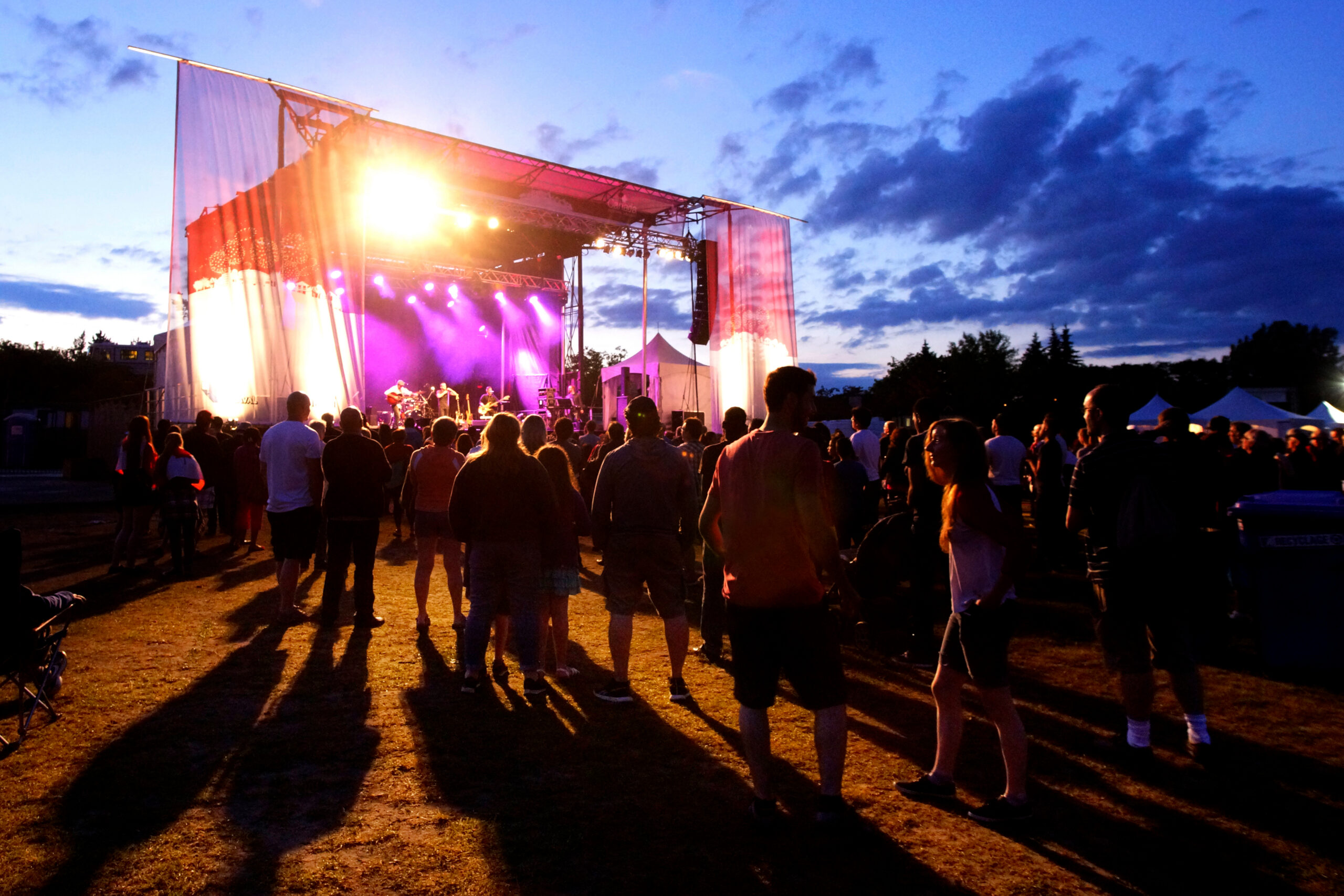 Summertime outdoor concert at night with a crowd watching a band onstage