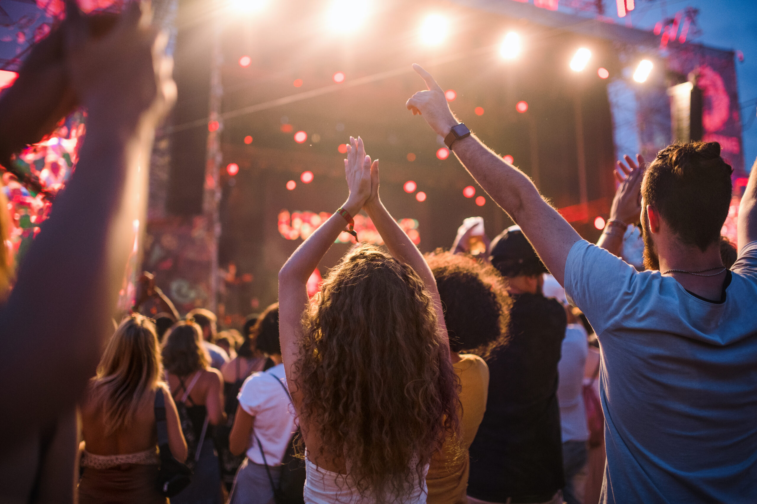 Rear view of group of unrecognizable young friends dancing at summer festival